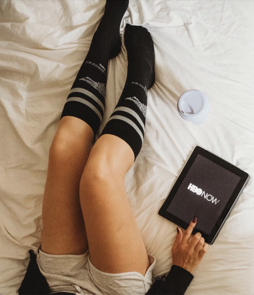 A woman is accessing HBONow on her iPad sitting in bed