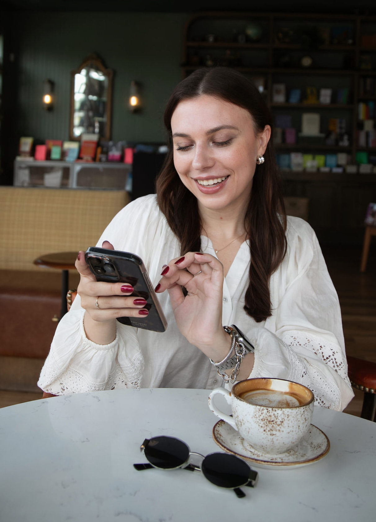 woman scrolls through phone at coffee shop